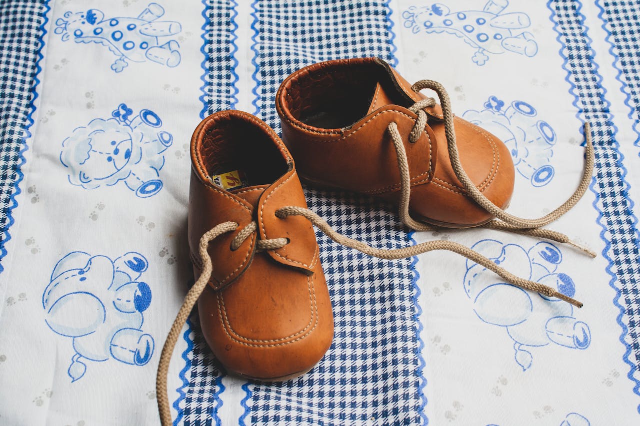 Close-up of cute brown leather baby shoes on a patterned blue blanket, perfect for baby themed projects.